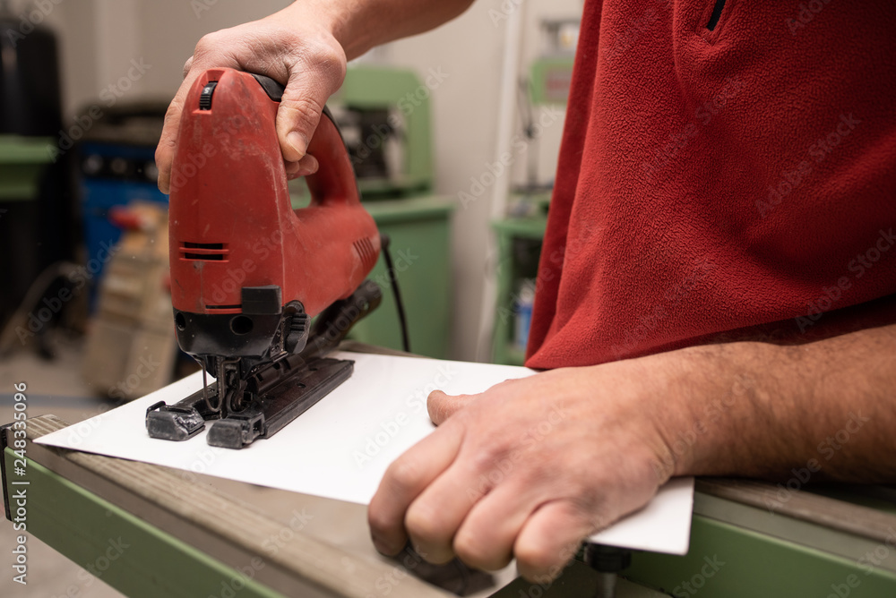 worker cutting an aluminium plate with a keyhole saw worker cutting an aluminium plate with a keyhole saw