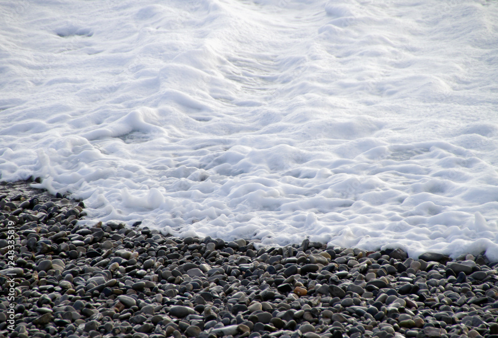 Ocean wave gushing over pebbles at the shore Ocean wave gushing over pebbles at the shore