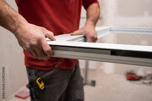 close up of worker assembling an aluminium door in workshop