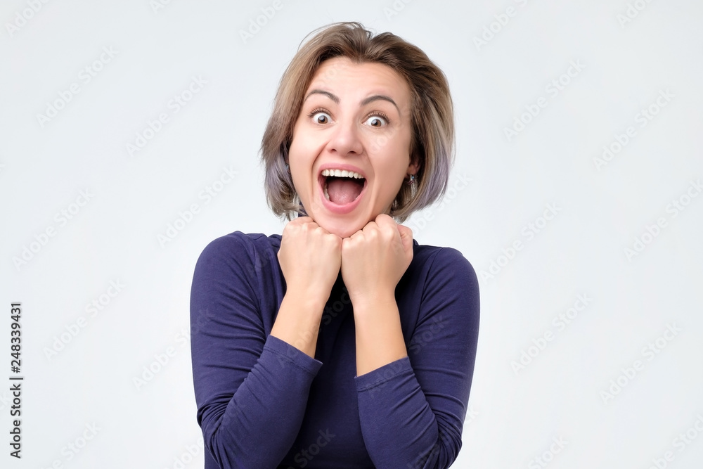 Cheerful, charming, pretty woman with wide open mouth, holding palms near face Cheerful, charming, pretty woman with wide open mouth, holding palms near face