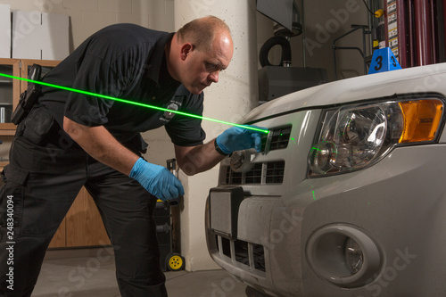 EMERGENCY SERVICES - Crime Scene Investigator using laser to study bullet trajectory evidence.
