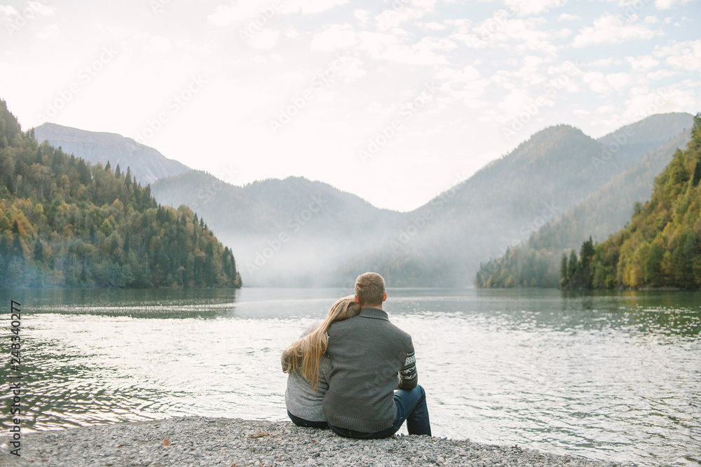 couple sitting on the edge of a lake