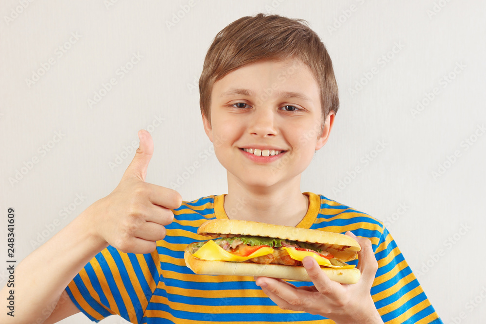Little cut boy recommends and likes tasty cheeseburger on a white background Little cut boy recommends and likes tasty cheeseburger on a white background