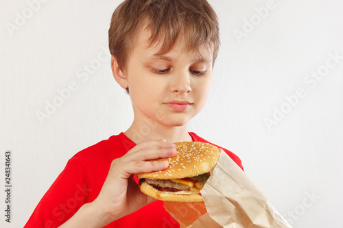 Little funny boy take out a hamburger from a package on a white background.