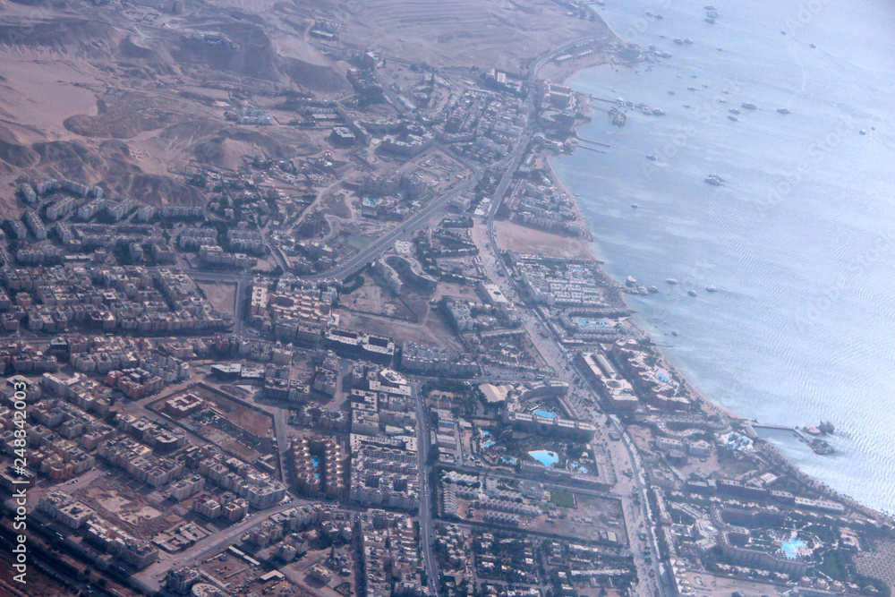 Aerial city view with houses, buildings, seaside in Egypt. Flying above country