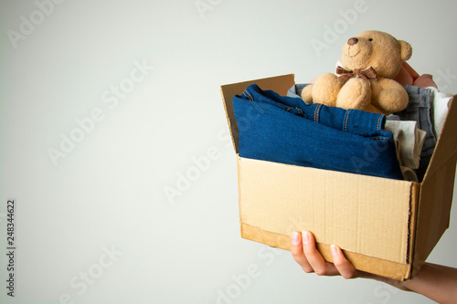 Donation concept. Hands holding donate box with clothes. Copy space. © Inga