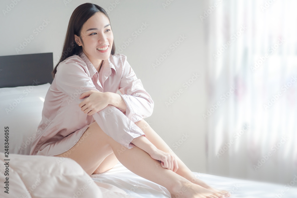 sexy women wearing pink pajamas, sitting and laughing on the bed in the morning. beautiful girl smile sexy women wearing pink pajamas, sitting and laughing on the bed in the morning. beautiful girl smile