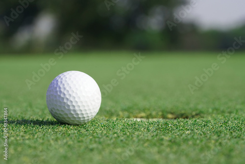 Close-up on a golf ball on a green grass near the hole