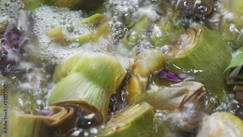 Boiling and cooking artichokes in saucepan, closeup