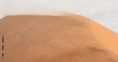 Red orange sand dune wave patterns with wind blowing sand over the dune, Sossusvlei, Namibia. Strong wind in the sand desert, pour. Landscape in Africa.