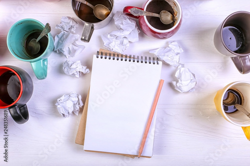 Obraz na plátne Empty dirty coffee cups, different colors on the table and a notebook for writing a letter