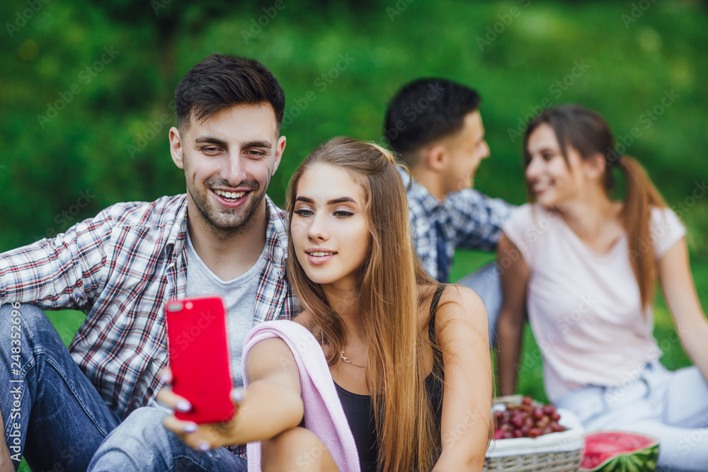 Two happy young couple sitting in grass at the beautiful park,they have a picnic Two happy young couple sitting in grass at the beautiful park,they have a picnic