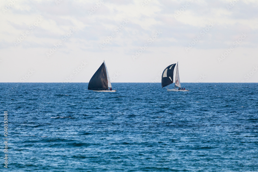 Yachts with blacks sails in the blue waters