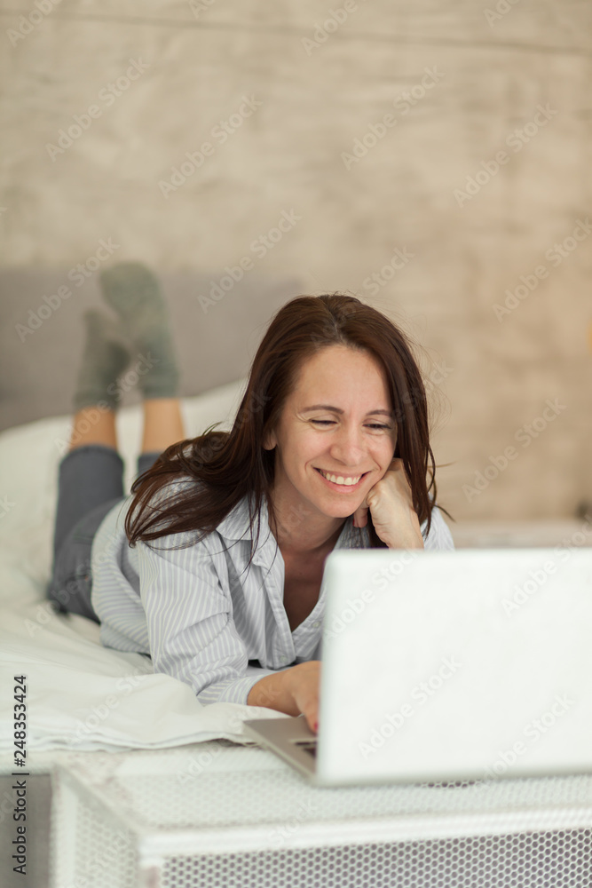 Mature brunette woman using laptop in bedroom Mature brunette woman using laptop in bedroom