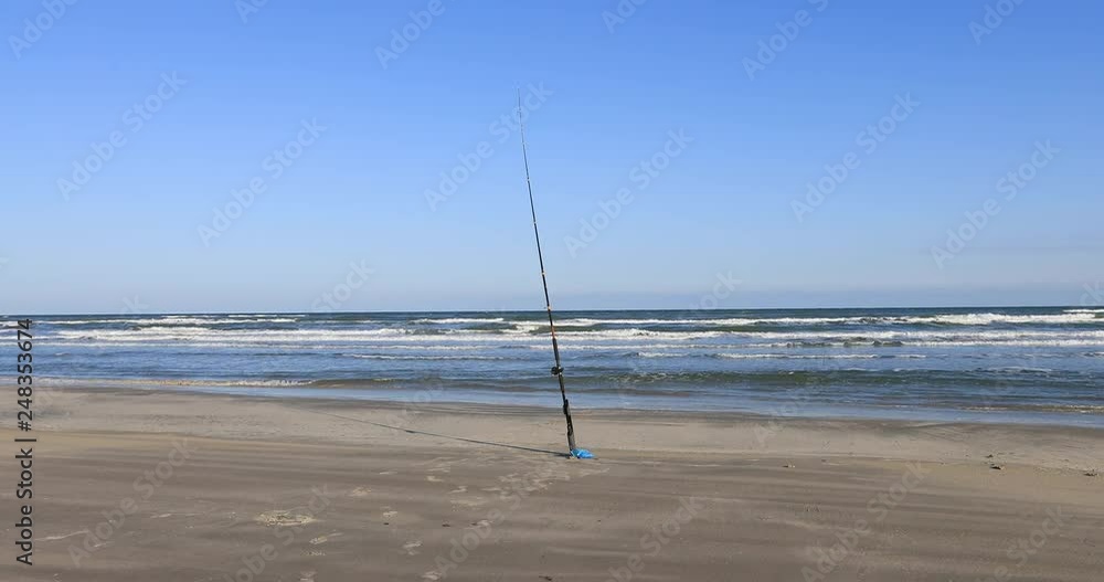 Man walking to fishing pole beach surf fishing Texas ocean. Beautiful