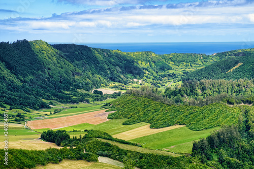 Landscape on Sao Miguel island of Azores, Portugal, with green mountains and Atlantic Ocean on skyline.