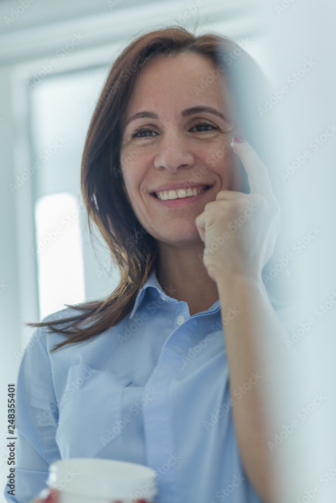 Perfect, pretty, woman applying eye cream in front of mirror Perfect, pretty, woman applying eye cream in front of mirror