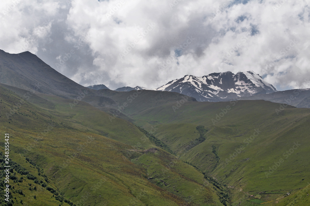 Fototapeta premium mountain landscape with peaks of mountains covered with snow and clouds