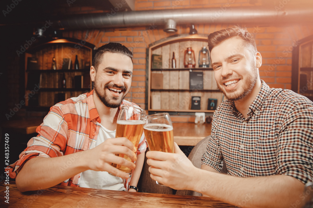 Meet cheerful friends at bar, drink draft beer in mugs and chat Meet cheerful friends at bar, drink draft beer in mugs and chat