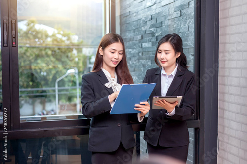 Two young businesswoman standing talking at meeting.