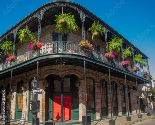 French Quarter architecture in New Orleans, Louisiana. House in French Quarter in 18th century Spanish style with cast iron galleries with hanging plants and pastel colors.  photo