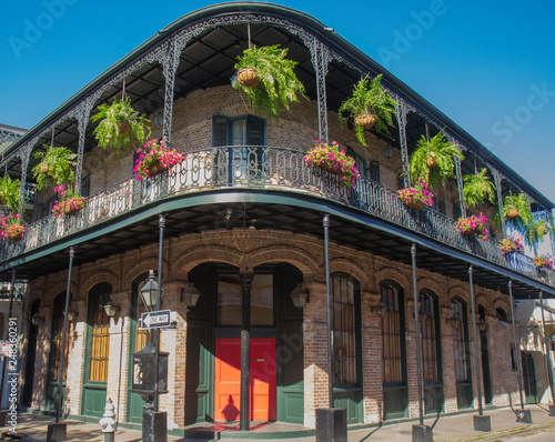 French Quarter architecture in New Orleans, Louisiana. House in French Quarter in 18th century Spanish style with cast iron galleries with hanging plants and pastel colors.  photo