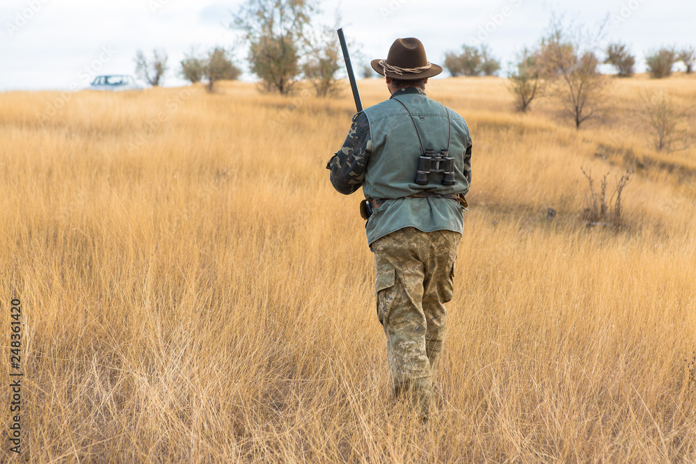 Hunter with a hat and a gun in search of prey in the steppe Hunter with a hat and a gun in search of prey in the steppe