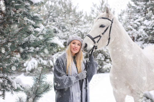 Young happy smiling attractive blond woman with horse, overcast winter day