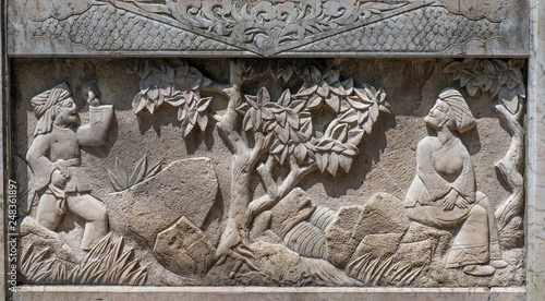 Stone relief panel showing tradional Chinese scene. Man, woman and tree, photo