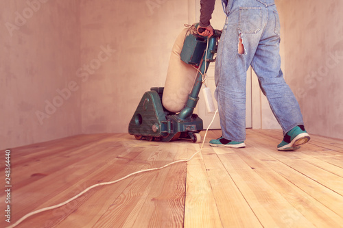 carpenter works by electric grinding wood machine in a room
