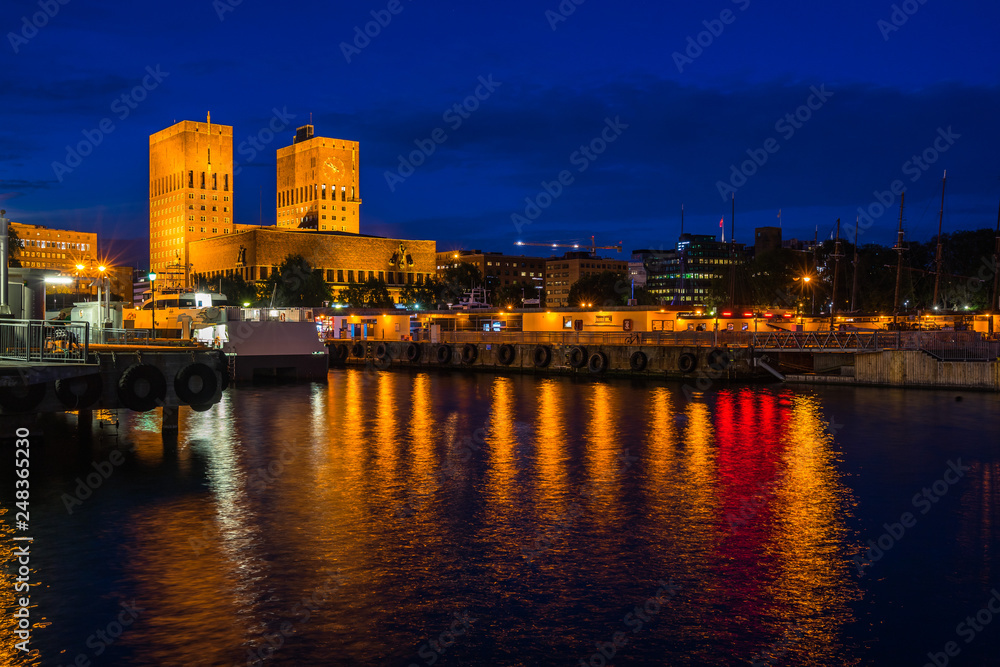 Night view of Oslo city hall (Radhus) a popular landmark of the city, facing the harbour and Oslofjord, Oslo, Norway