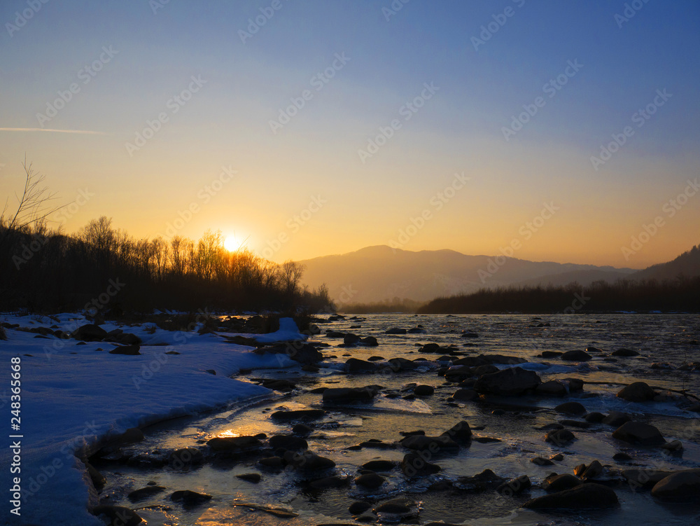 Mountain river in winter. Ice. Sunset. The mountains. River
