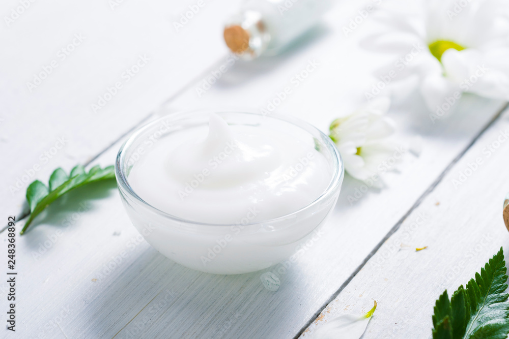 spa setting with cosmetic cream, gel, bath salt and fern leaves on white wooden table background spa setting with cosmetic cream, gel, bath salt and fern leaves on white wooden table background