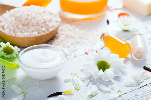 aromatherapy: orange gel and extract, bath salt, cosmetic cream, organic soap and petals on white wood