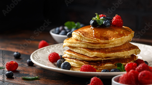 Homemade american pancakes with fresh blueberry, raspberries and honey. Healthy morning breakfast. rustic style photo