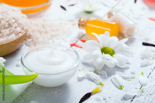 aromatherapy: orange gel and extract, bath salt, cosmetic cream, organic soap and petals on white wood