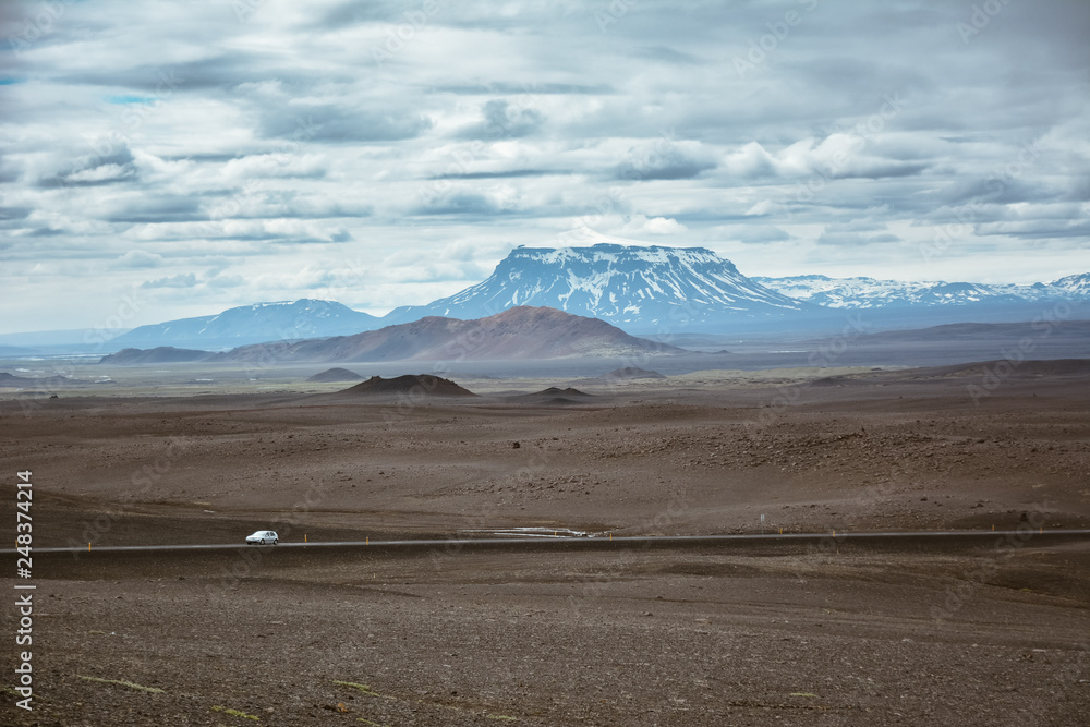 Typical ring road view with empty road and snowy mountains and one lonely car in Iceland in summer Typical ring road view with empty road and snowy mountains and one lonely car in Iceland in summer