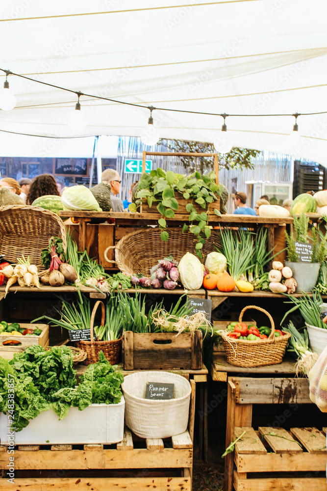 Fototapeta premium Vegetables and fruits on wooden shelf being sold at the Oranjezicht City Farm Market in Cape Town, South Africa