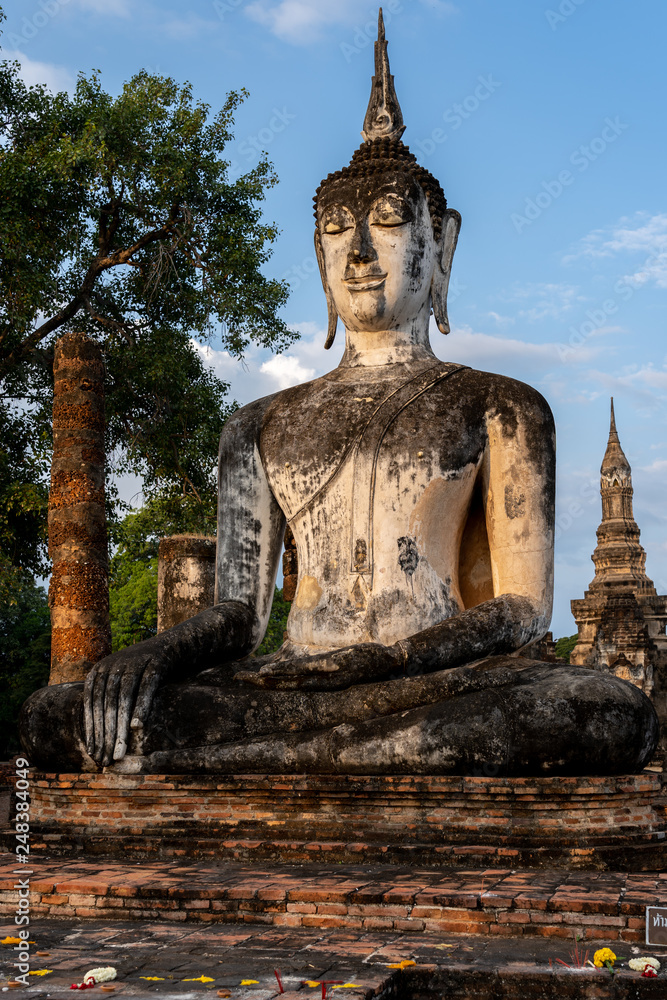 Fototapeta premium Buddha Statue in the morning at wat mahathat in Sukhothai Historical Park, Thailand, one of Thailand's most impressive World Heritage Sites, includes the remains of 21 historical sites. 