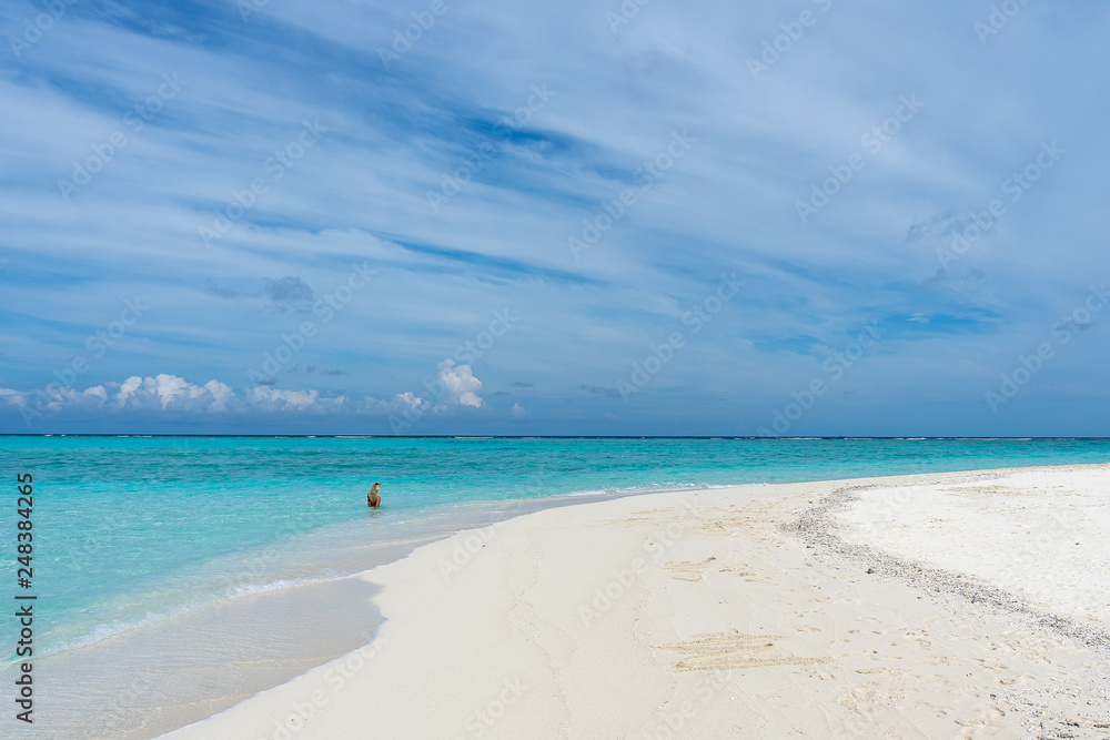 Sandbank with an unrecognized young woman in background in Maldives.  