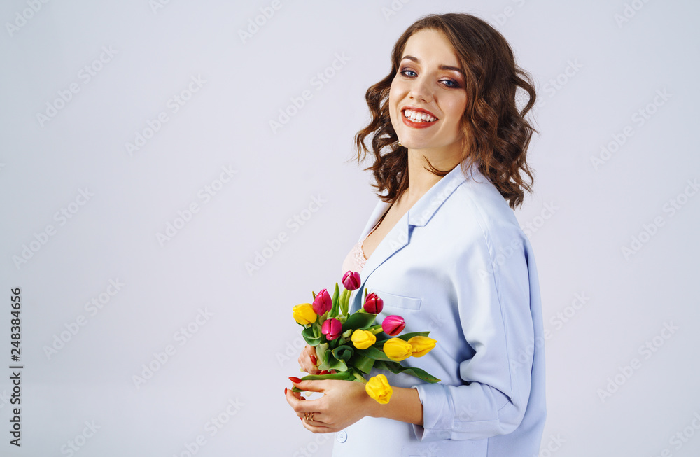 Fashion photo of a beautiful young woman with tulips in her hand .she dressed in a beautiful coat, and T-shirt with stripes.Spring concept. March 8. beautiful girl in stylish clothes Fashion photo of a beautiful young woman with tulips in her hand .she dressed in a beautiful coat, and T-shirt with stripes.Spring concept. March 8. beautiful girl in stylish clothes