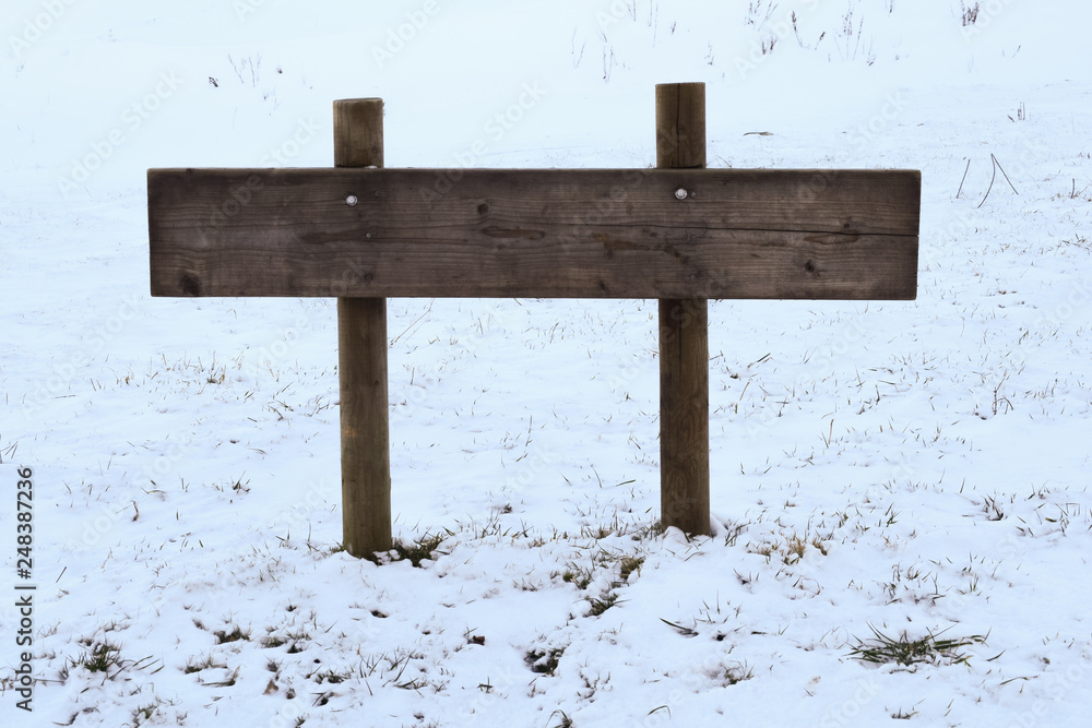 Naklejka premium Wooden pointer on the background of the winter landscape. Copy space