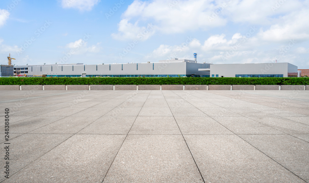 Empty square floor tiles and modern factory buildings and warehouses..
