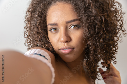 Selfie portrait of cheerful black woman in studio with curly hair