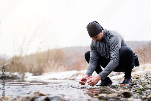 Man By The RIverside, Drinking water from the river, Ultra trail runner refreashing in winter training