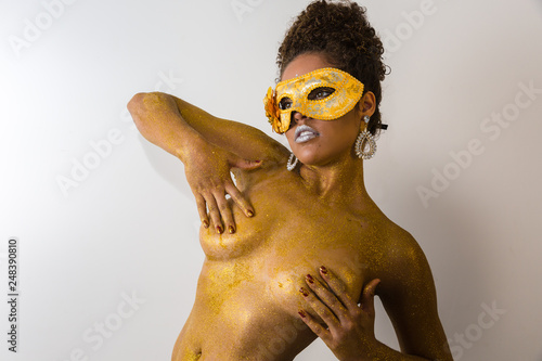 Beautiful Brazilian afro girl ready for the carnival. Golden body painting. Fashion girl with carnival mask. photo