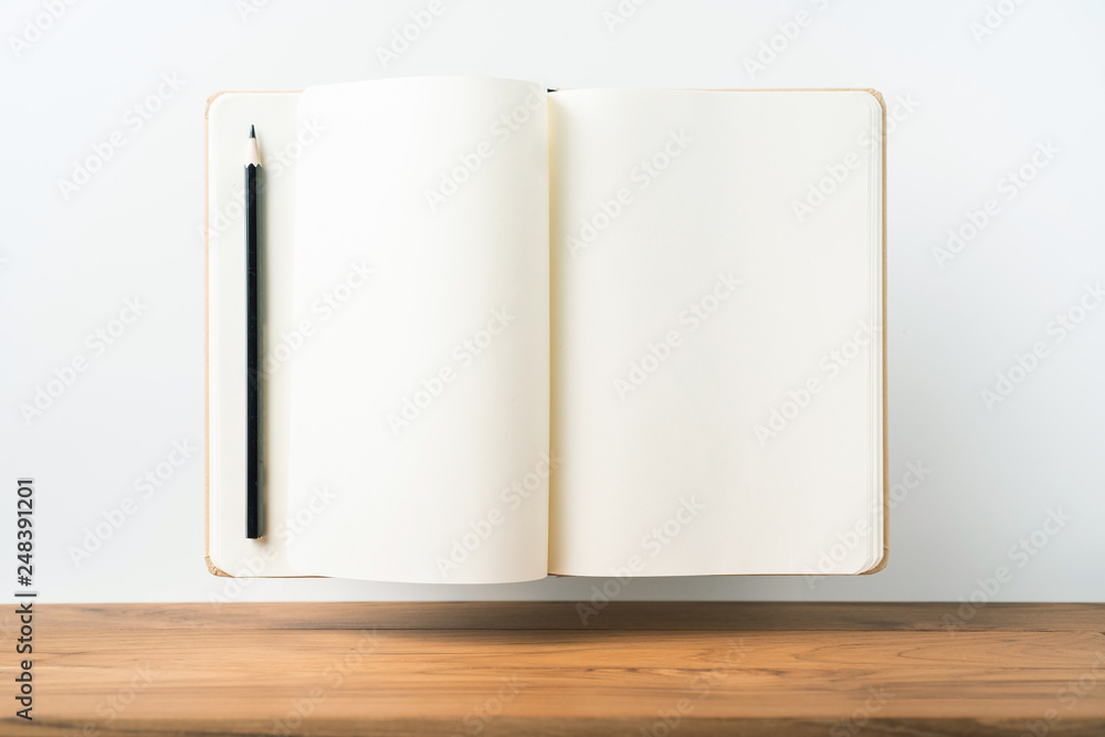 Perspective view of kraft notebook on wood floor Perspective view of kraft notebook on wood floor
