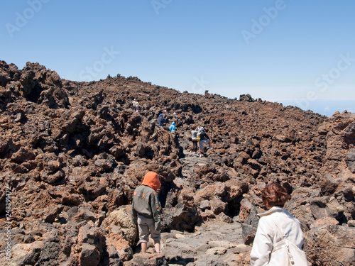 Tourists walking through stones and volcanic rocks © Carlos Dominique
