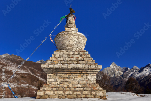 White Tibetan Prayer Stupa, Tibetan Prayer Flags - Picturesque winter scenery - Four Girls Mountain National Park in Sichuan Province, China. Snow Capped Yaomei Peak in distance. Siguniangshan