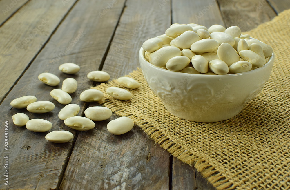 white beans on a wooden table and a jute napkin white beans on a wooden table and a jute napkin